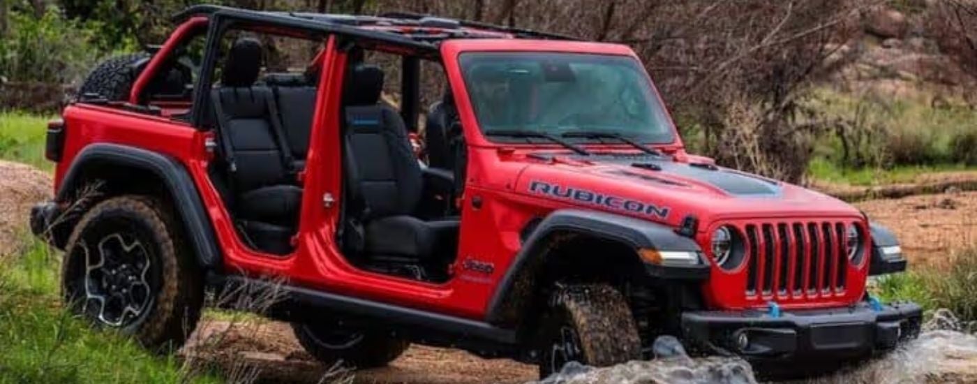 A red 2023 Jeep Wrangler Rubicon 4xe parked off-road.