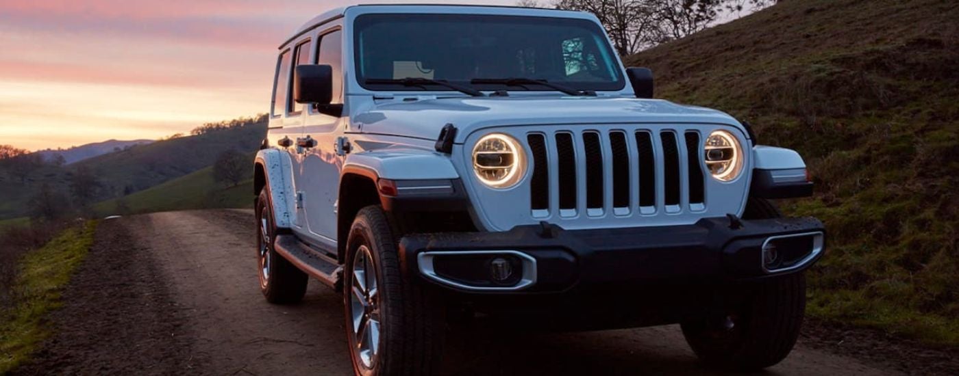 A white CPO 2019 Jeep Wrangler driving at sunset.