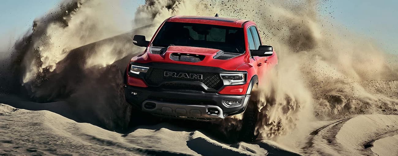 Red 2021 Ram 1500 TRX driving off-road on a hill.