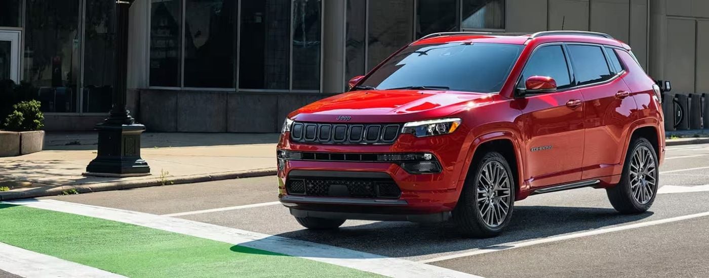 Red 2023 Jeep Compass driving through a city