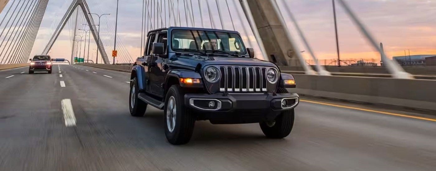 Black 2023 Jeep Wrangler Unlimited driving to see a used Jeep for sale near Holly