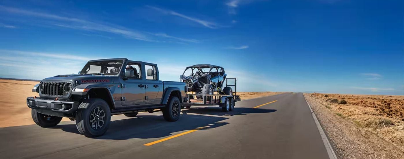 Silver 2024 Jeep Gladiator towing an ATV