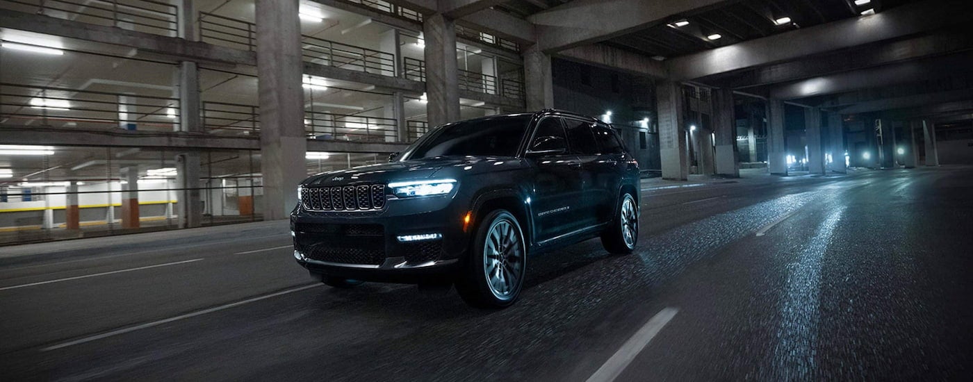 Black 2026 Jeep Grand Cherokee driving down an open road.