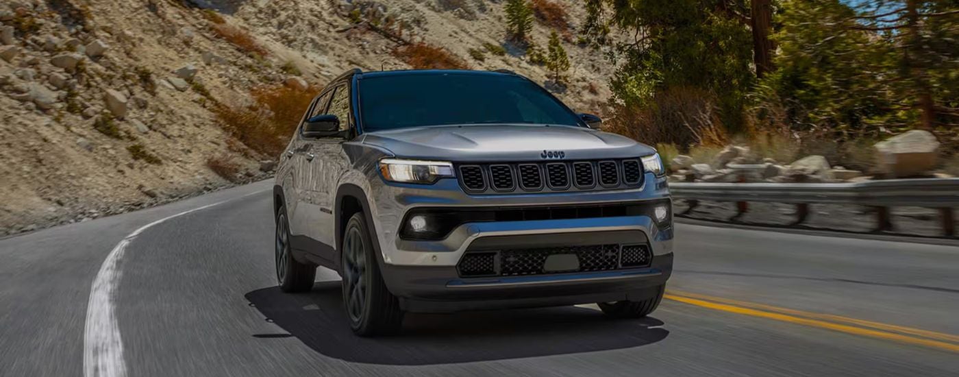 Silver 2026 Jeep Compass Limited Altitude driving on a paved road.