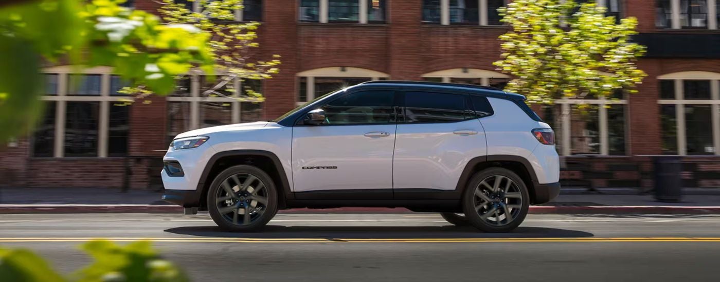 Side view of a white 2026 Jeep Compass Limited Altitude on a city street.