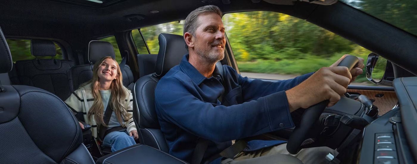 Interior view of a father driving his daughter in a 2026 Jeep Grand Cherokee.