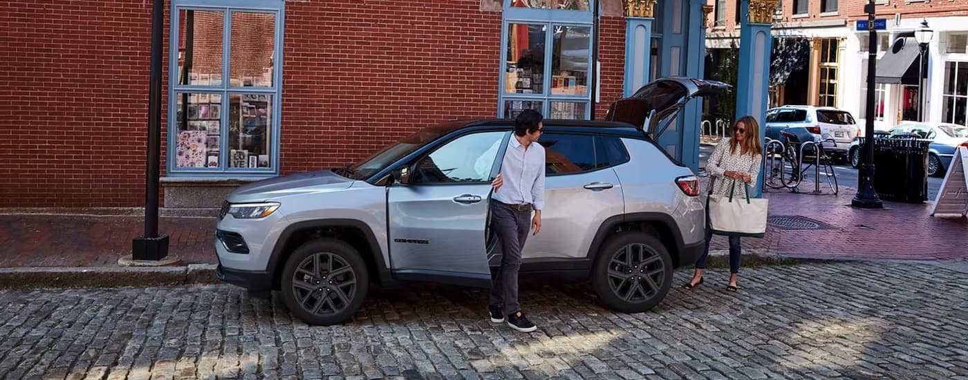 People exiting a silver 2026 Jeep Compass.