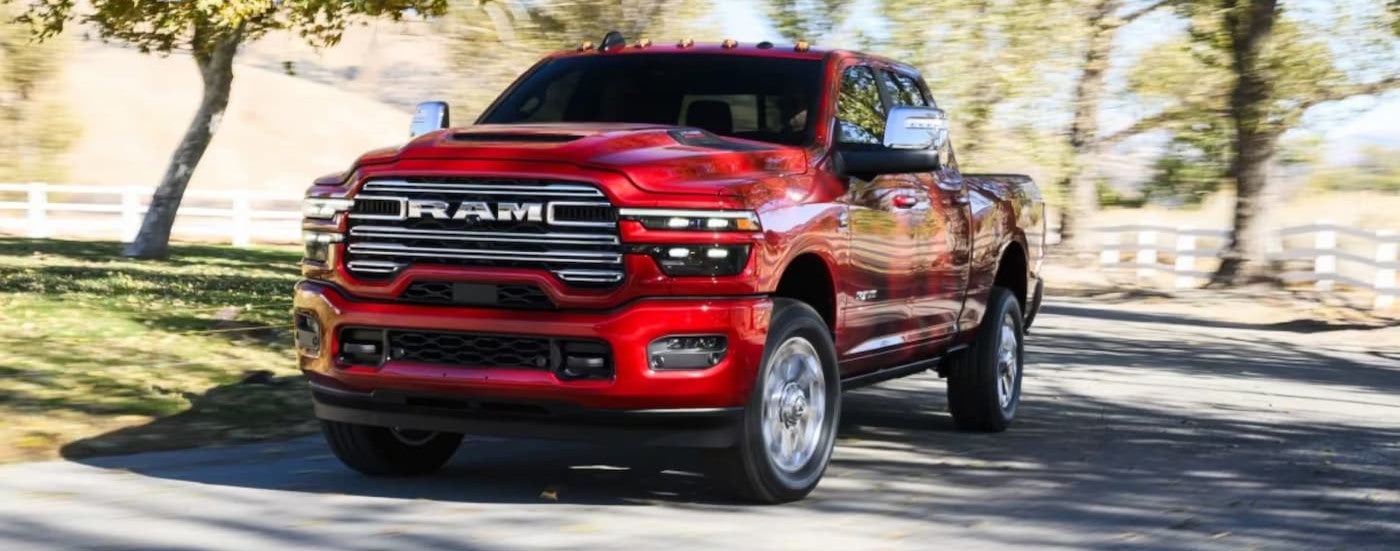 A red 2026 Ram 2500 driving to a Ram dealer near Holly.